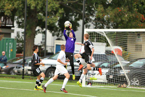 SENIOR GOALIE Tyler Strauss (middle) goes up for a shot amid a pair of Winchester and Warrior players. Strauss made 13 saves, many of the sensational variety as the WMHS boys’ soccer team upset Winchester, 1-0, yesterday at Walton Field. (Donna Larsson Photo)