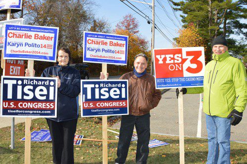 A SUNNY DAY at the polls. Election volunteers holding campaign signs in front of St. Theresa Church on Tuesday had great weather and met many voters. From left: Joyce Jenney, Jeff Yull and Kris Mineau. (Bob Turosz Photo)