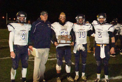 TO THE VICTOR goes the spoils. Showing off the team's D4 North Championship trophy are, from left: Pioneer captain Cam Rondeau (8), head coach Neal Weidman and captains David Adams (56), Jon Knee (10), and Danny Sullivan (2). (Tom Condardo Photo)