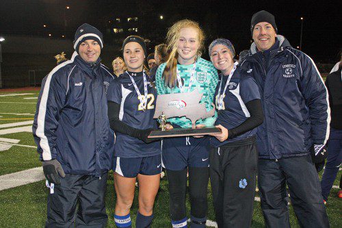 THE GIRLS’ SOCCER TEAM were full of smiles while accepting the Division 3 state championship runner-up trophy after falling 5-0 to Nipmuc Regional High School at Worcester Polytechnic Institute’s Alumni Stadium Nov. 21. Proudly accepting the trophy are, from left, assistant coach Darren Damiani, senior captains Emily Scollard, Hannah Travers and Paige MacEachern and head coach Mark Vermont. (Dan Tomasello Photo)