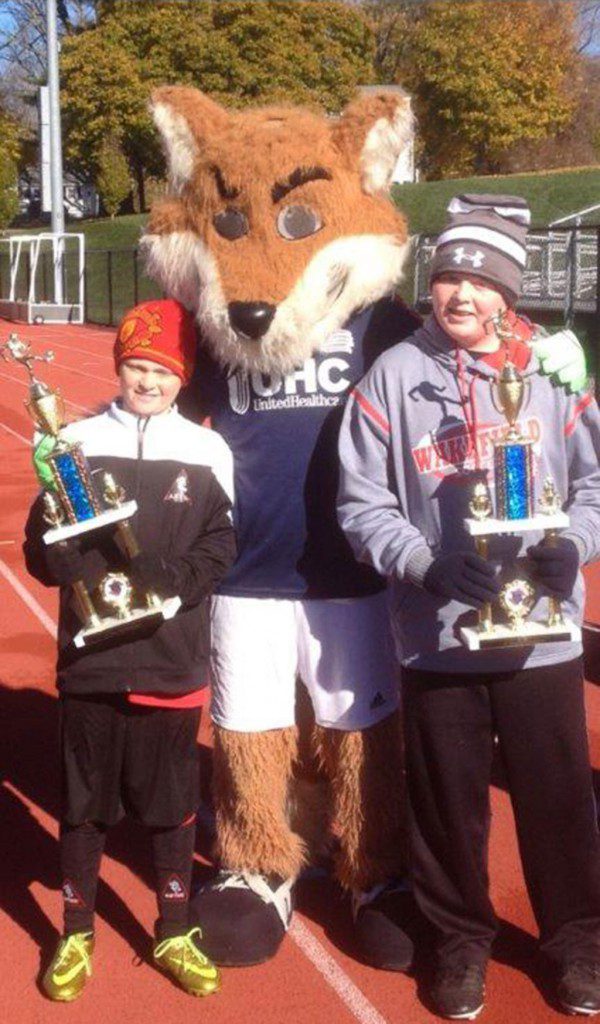 KNIGHTS OF Columbus state soccer champs William Townshend (left) and Liam Cosgrove (right) show their championship trophies to Slyde, the mascot for the New England Revolution soccer team.