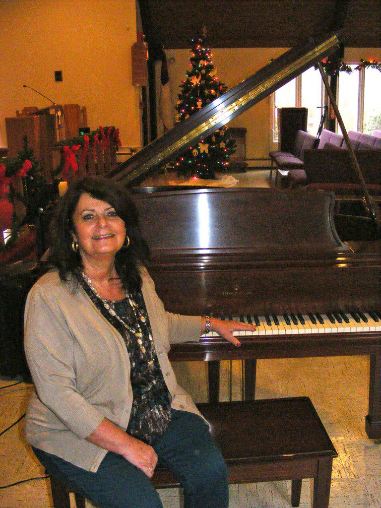 EBONY AND IVORY. Beth Connors, the President of the North Reading Community Chorale sits beside the 6 foot Steinway piano newly installed at Aldersgate Church. (Courtesy Photo)