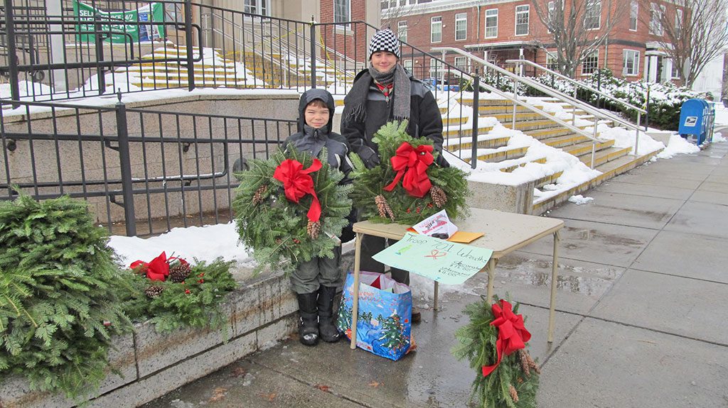 BRAVING the cold on Friday while selling wreaths for Boy Scouts Troop 701 in front of the Post Office on Main Street were Alex Skeldon, left, and Michael Constas. Alex is a sixth grade student at the Galvin Middle School; Michael is in ninth grade at St. John’s Preparatory School in Danvers. Sales will continue this coming Saturday at the Most Blessed Sacrament Church in Greenwood, Honey Dew Donuts and during the Holiday Stroll. On Sunday morning, they will be at the Emmanuel Episcopal Church on Bryant Street. (Gail Lowe Photo)