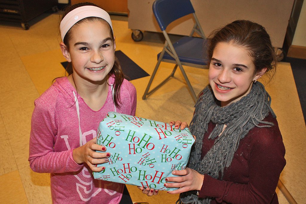 SIXTH GRADERS Julia Colucci (left) and Mary Indresano proudly display a wrapped gift that will be donated to a needy family during the eighth annual middle school holiday gift drive Dec. 17. (Dan Tomasello Photo)