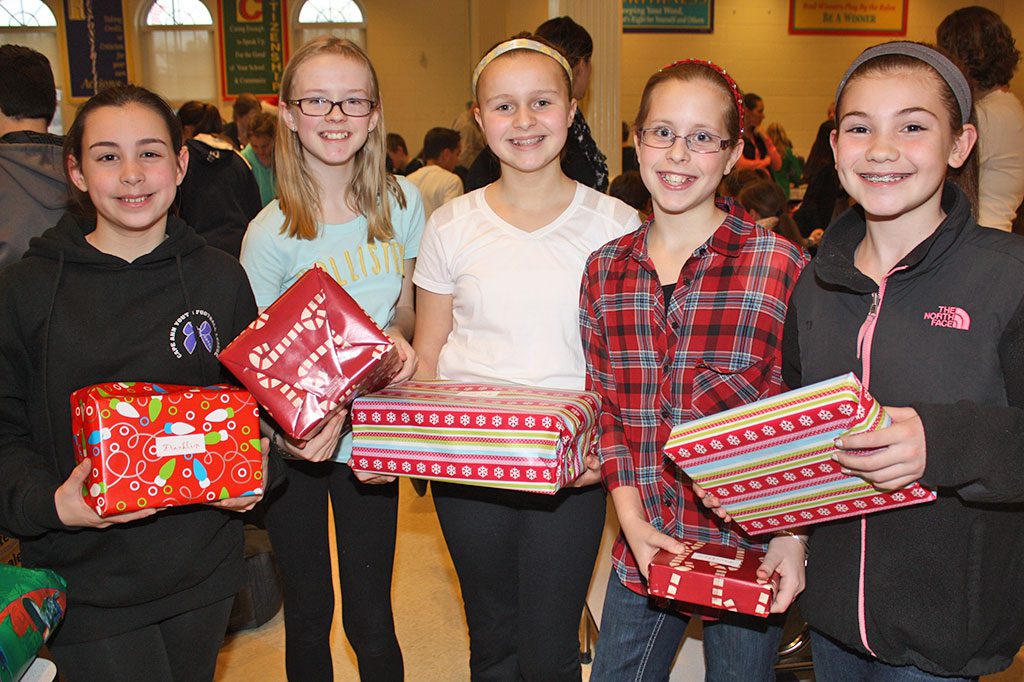 MIDDLE SCHOOL students, from left, Grace Magno, Grace Mealey, Emily Goguen, Brooke Adams and Ella Gaudette proudly display gifts they wrapped during the middle school’s eighth annual holiday gift drive Dec. 17. (Dan Tomasello Photo)