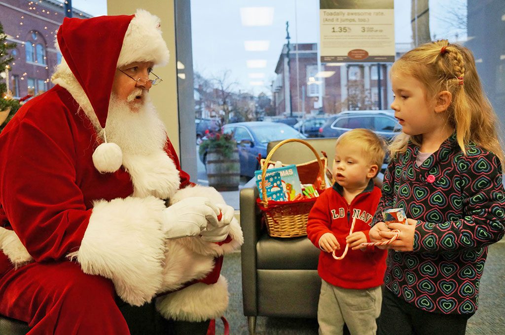LANEY AND CALLEN DWYER, grandchildren of Wakefield resident Nancy Dwyer, enjoy the holiday spirit and Santa’s “Rudolph the Red Nose Reindeer” magic trick at Wakefield Co-operative Bank last week.