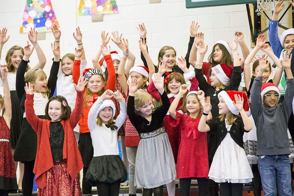 THIRD GRADE STUDENTS at the Little School have their hands in the air for the joy of the holidays during the school's Winter Concert last week. (Suzanne Baker Photo)