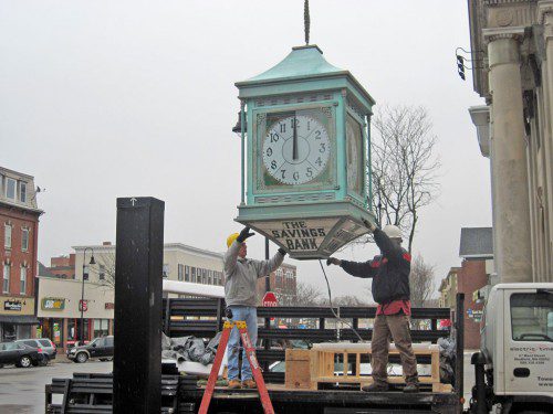 THE Savings Bank clock, a fixture on Main Street for many years, was hoisted back into place Monday morning at the corner of Chestnut and Main streets after being sent out for service in the fall of 2014. (Gail Lowe Photo)