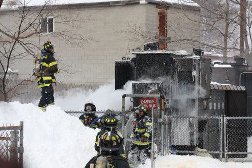 A firefighter scrambled atop  A five-foot high snowbank at the Wakefield Avenue substation to determine if all the flames have been knocked down. (Maureen Doherty Photo)