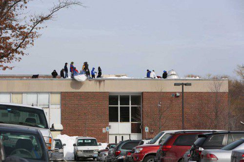 WAKEFIELD MEMORIAL HIGH SCHOOL opened after a week’s vacation this morning. Here, crews hired by the town clear off part of the building’s roof over the weekend. (Donna Larsson Photo) 