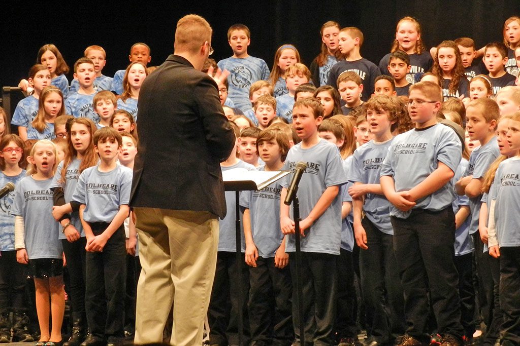 THE GALVIN MIDDLE SCHOOL’S Memorial Auditorium came alive last night as the Wakefield Music Department presented the 4th Grade Choral Concert featuring students from the Dolbeare, Walton, Greenwood and Woodville schools. Here, they sing the finale “Hi Ho! The Rattlin’ Bog” under the direction of Christopher Zini, one of the elementary schools’ music teachers. (Colleen Riley Photo)