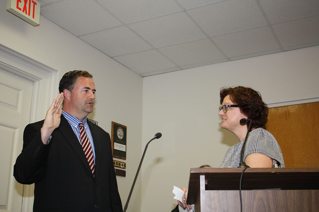 NEW SELECTMAN Christopher Barrett takes his oath of office Monday night at the swearing-in ceremony by Town Clerk Trudy Reid moments after the results of the annual election gave him the edge over opponent Katy Shea by 39 votes. (Maureen Doherty Photo)