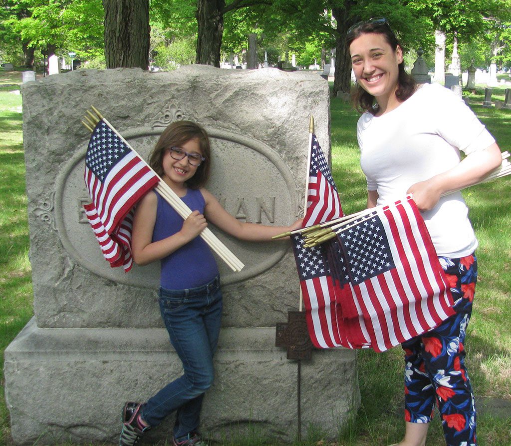 WAKEFIELD VETERANS SERVICE Officer Alicia Reddin and her daughter, 7 year old Rosalie, place a flag at a veteran’s grave at Lakeside Cemetery on Monday. Led by members of American Legion Post 63, dozens of scouts and other volunteers placed American flags at the graves of veterans in an annual pre-Memorial Day tradition. On Friday at 4 p.m., flags will be placed on veterans’ graves at Forest Glade Cemetery. Anyone who would like to volunteer is encouraged to join the effort. (Mark Sardella Photo)