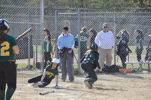 SAFE AT THE PLATE. Carly Swartz reaches back to touch home plate while the Manchester–Essex catcher is still searching for the ball. North Reading won, 12–0. (Bob Turosz Photo)