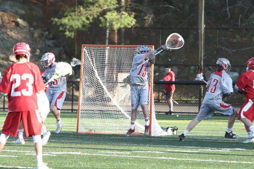 ALEX FLYNN, a senior (#19), had a strong game in goal for Wakefield as he goes up to catch the ball on a shot just wide of the net. Helping defend the play is Ned Buckley (#13). The Warriors prevailed by an 11-5 score against Melrose. (Donna Larsson Photo)