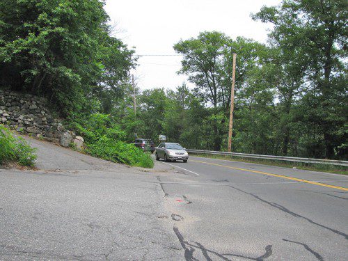 THIS view from a vehicle pulling out of Gianna Drive shows that a mound of earth and vegetation block a driver’s ability to see traffic on Walnut Street approaching from the left. Residents at last week’s traffic meeting told the selectmen that they were worried about a serious accident occurring at this location. A traffic study conducted by the BETA Group concluded that a more intensive engineering review would be required to determine the best way to rectify this problem. (Mark Sardella Photo)