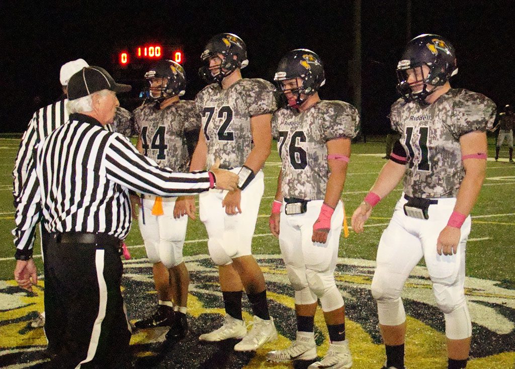SPORTING special camouflage jerseys in honor of the town's military personnel, Pioneer captains Drew McCarthy (1), Drew Balestrieri (44), Cam DeGeorge (72), Spencer Balian (76), and CJ Finn (11) acknowledge the referees prior to Friday's coin toss. (Tom Condardo Photo)