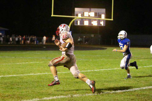 PAUL McGUNIGLE, a senior running back (#42), outraces Stoneham DB Brendan O'Neil (#23) to the end zone on a 30 yard touchdown run. McGunigle also added the extra point as the Warriors prevailed by a 7-6 score for their first win of the season. (Donna Larsson File Photo)