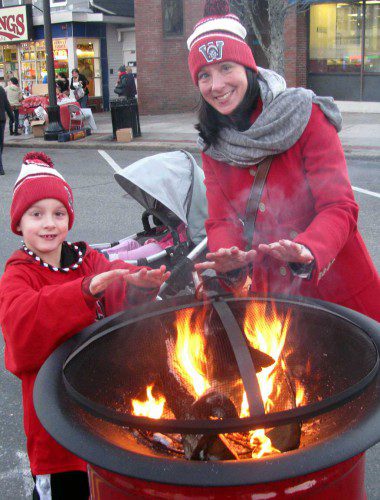 BRIAN WESTON and mom Heather stop to warm their hands at one of the fire barrels at the Holiday Stroll. (Mark Sardella photo)