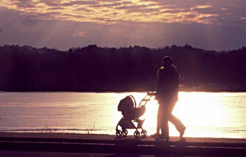A COUPLE pushing a stroller along the sidewalk near Beebe’s Cove is silhouetted by the bright sun reflected off the ice. (Mark Sardella Photo)