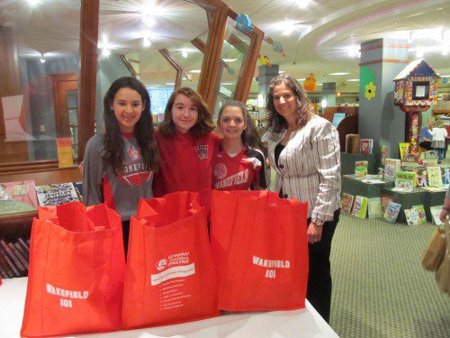 HELPING TO PASS out tote bags filled with items newcomers to Wakefield might need were, from left: Elianna Cohen, Casey MacGibbon and Nicole Calandra. All three girls are members of the Junior Honor Society and attend classes at the Galvin Middle School. They are shown with Wakefield Lynnfield Chamber of Commerce Director Marianne Cohen. (Gail Lowe Photo)