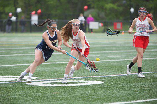 KELSEY CZARNOTA, a junior (#3), battles a Lynnfield player for the ball last night Landrigan Field. Czarnota also scored a goal. Senior Brianna Smith (#11), led the Warrior offense as she tallied four goals in Wakefield’s 13-3 rout over the Pioneers. (Donna Larsson Photo)