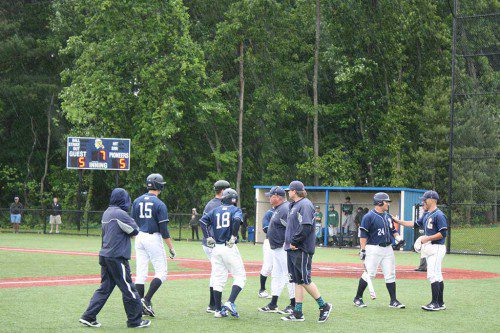 PIONEERS GATHER with their coach, John O'Brien (center), as an unrelenting downpour caused a rain delay to be called by the umpires in the bottom of the seventh with the score knotted at 5-5 in Sunday’s Div. 3 North first round tournament game against Pentucket. (Maureen Doherty Photo)