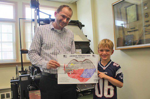 WITH AN ear-to-ear grin, 6-year-old Michael Barrett accepts his prize in the Villager’s coloring contest from John Keating, a graphic artist at the newspaper who designed the contest entry. Michael won a $50 gift certificate to Meletharb’s Ice Cream as the winner in the 6 and under age group. (Maureen Doherty Photo)