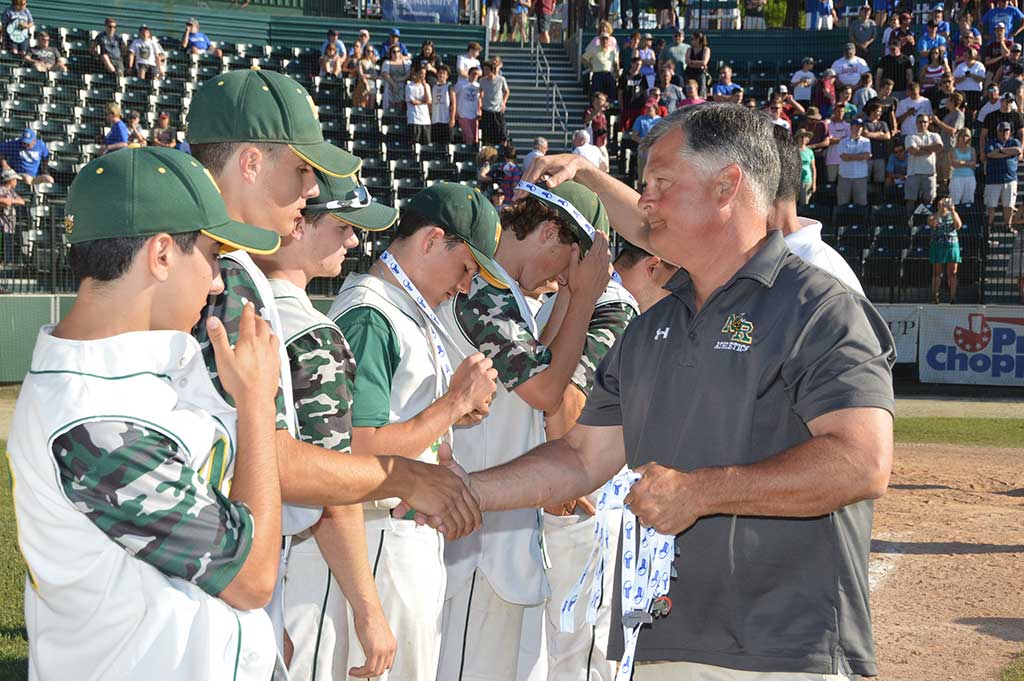 NRHS ATHLETIC DIRECTOR Dave Johnson is proud of the school’s baseball team as he distributes Division 3 state championship medals after the game. But the boys’ glum faces tell the story that they lost to Groton–Dunstable, 5 to 4. (Bob Turosz Photo)