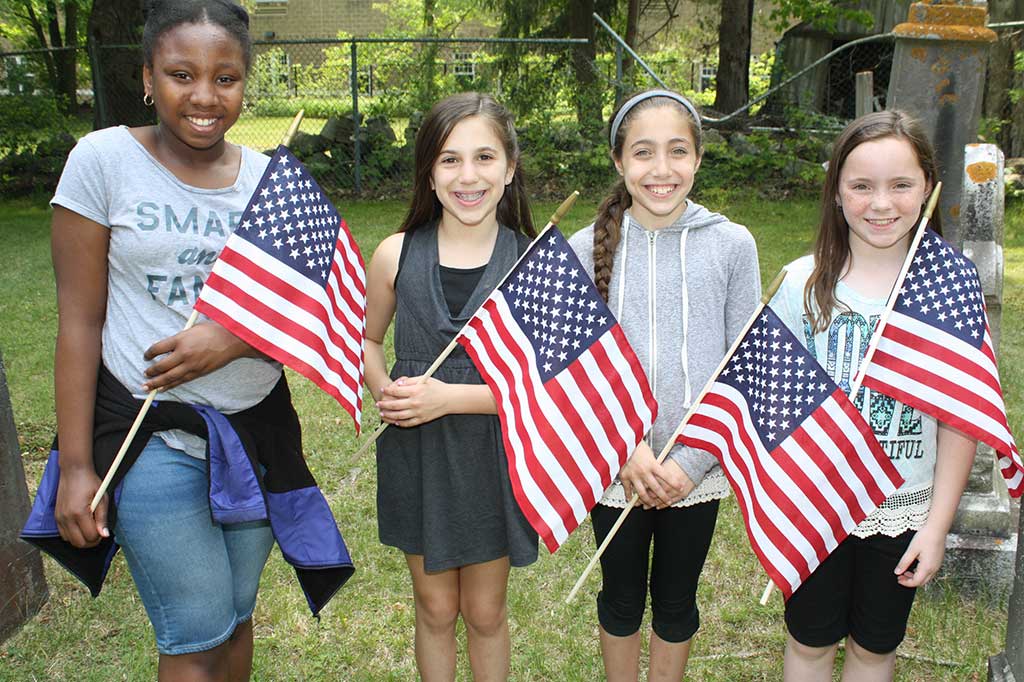 FIFTH-graders, from left, Saniyah Charles, Ava Zalvan, Emily Palumbo and Maggie Reardon placed these American flags next to the graves of Revolutionary War veterans at the West Burying Ground cemetery May 27 in advance of Memorial Day. (Dan Tomasello Photo)