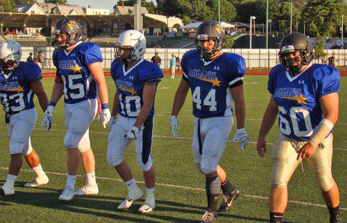 CJ FINN (45) and Drew Balestrieri (44) head out for the coin toss before the 55th annual Agganis Football Classic June 30. The pair was elected by their teammates as two of the five North captains. The North fell 27-19 to the South at Lynn’s Manning Field. (Tom Condardo Photo)