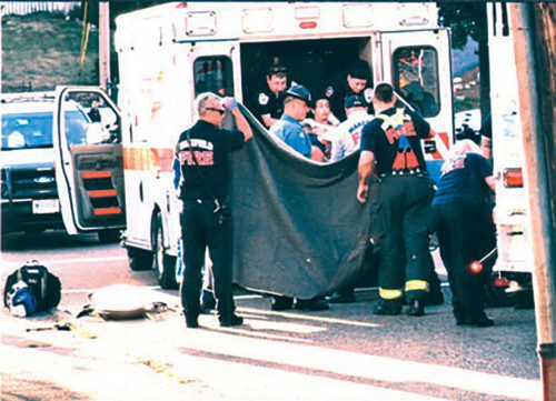 WAKEFIELD FIREFIGHTERS and Action Ambulance EMTs remove the victim of yesterday’s Breakheart stabbing from the ambulance before carrying him on a stretcher to a waiting MedFlight helicopter on Walsh Field for the flight to Beth Israel Deaconess Medical Center in Boston. (Don Young Photo)
