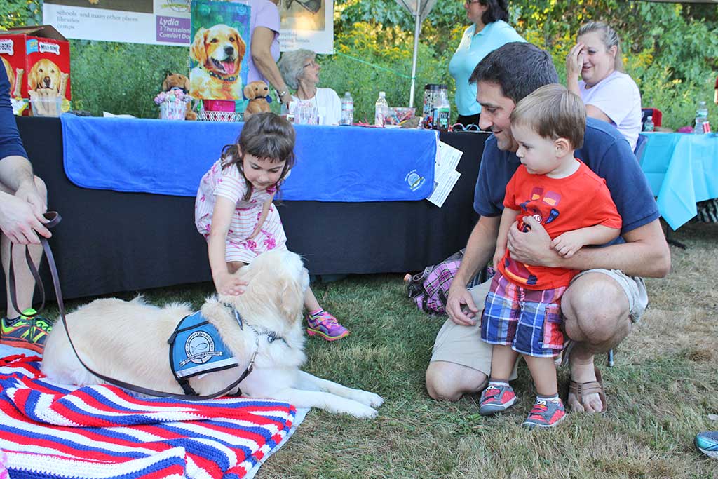 LYDIA the comfort dog was a hit with young and old alike at the town’s National Night Out festivities Aug. 2. Casey Fishman, 5, gently pats Lydia while her brother AJ, 2, waits for his turn with their dad Rob. (Maureen Doherty Photo)