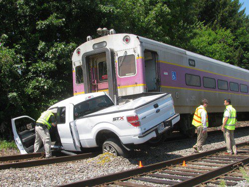 AN MBTA Police investigator examines the cab of a Ford F-150 that was struck by a Boston-bound commuter rail train late yesterday morning at the Broadway crossing. (Mark Sardella Photo) 