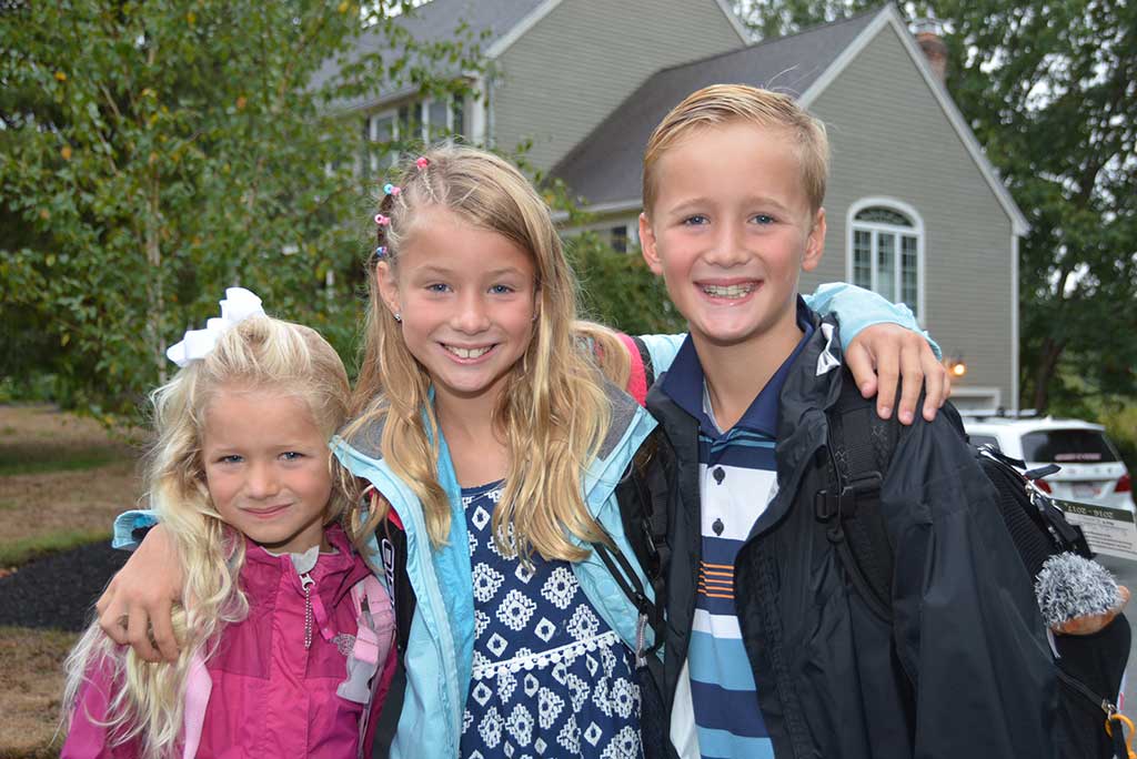 THE THREE OOSTMAN children, Maeve, (grade one), Kyla, (grade 3) and Rowan, (grade 5), were all smiles waiting for the bus on the first day of school to take them to the Batchelder School. (Bob Turosz Photo)