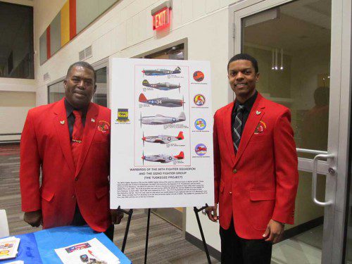 TUSKEGEE AIRMEN Galen Williams (left) and Yemoni Huguely are shown standing next to a poster describing the aircraft flown during World War II.
