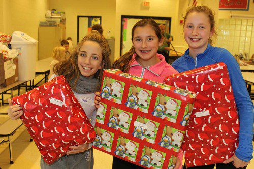 CLASSMATES, from left, Elizabeth Schmidt, Anna Kaminski and Lily Conway show off wrapped presents during Lynnfield Middle School’s annual holiday gift drive Dec. 20. The LMS community donated around 1,500 gifts to needy families this year. (Dan Tomasello Photo)