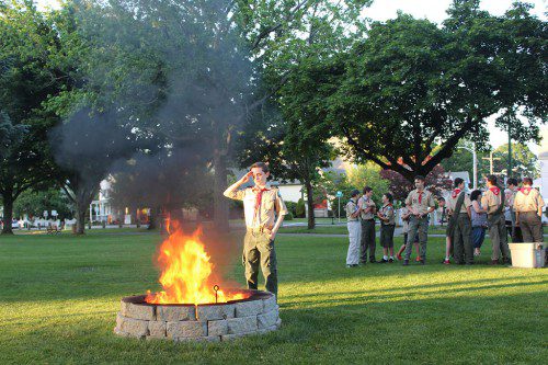 A MEMBER OF Boy Scout Troop 701 gives a Scout salute while retiring an old flag during a Flag Day ceremony hosted by the Corp. Harry E. Nelson American Legion post last night on the Veterans Memorial Common. (Colleen Riley Photo)