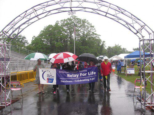 CANCER SURVIVORS and caregivers were not about to let Friday’s cold rain keep them from walking the Survivors’ Lap at Friday’s Relay For Life of Wakefield. More photos appear inside today’s paper. (Mark Sardella Photo)