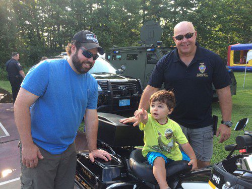 Officer Scott Tilton shows the police motorcycle to Mike and Garrett Rogers during Monday evening’s National Night Out celebration at Ipswich River Park. (Bill Laforme photo)